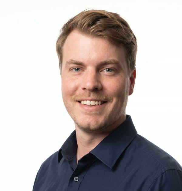 Professional headshot of Allan in a navy shirt against a plain light-gray backdrop